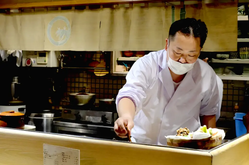 Ramen chef preparing dishes behind restaurant counter.