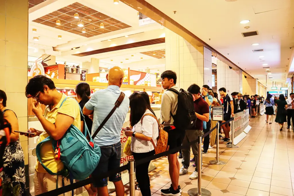 Long queue of people waiting outside a popular ramen shop in Singapore