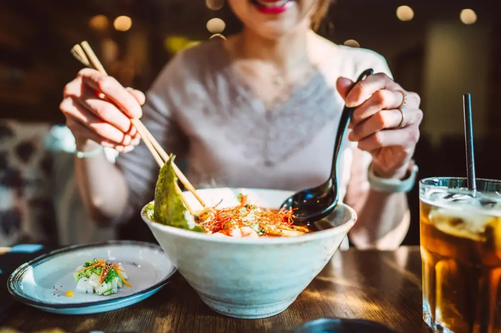 Person enjoying a bowl of ramen in a cozy restaurant setting in Singapore