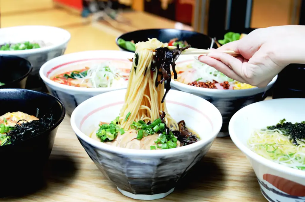 Assorted ramen bowls with noodles lifted by chopsticks showcasing variety and texture in a Japanese restaurant