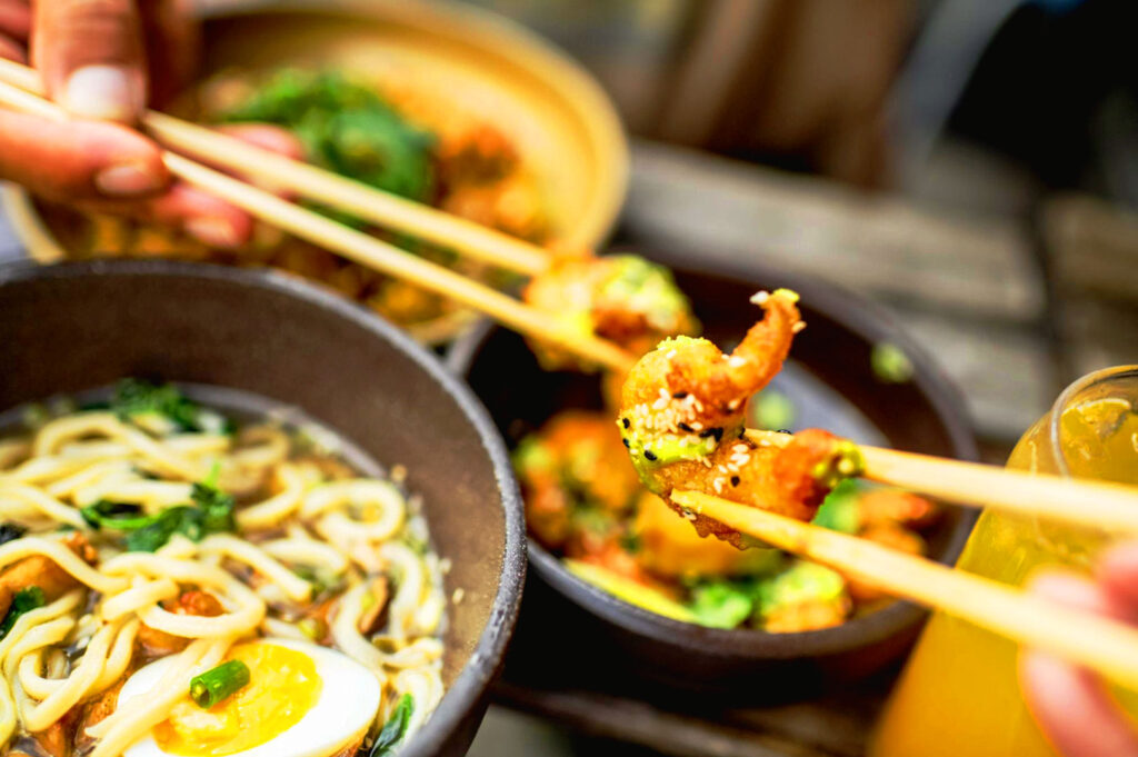 Close-up of laksa-style ramen with creamy spicy broth, soft-boiled egg, seaweed, and chashu pork