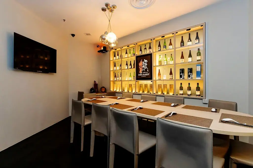 Japanese ramen restaurant private dining room in Singapore with minimalist interior, sake bottle display wall and modern izakaya seating