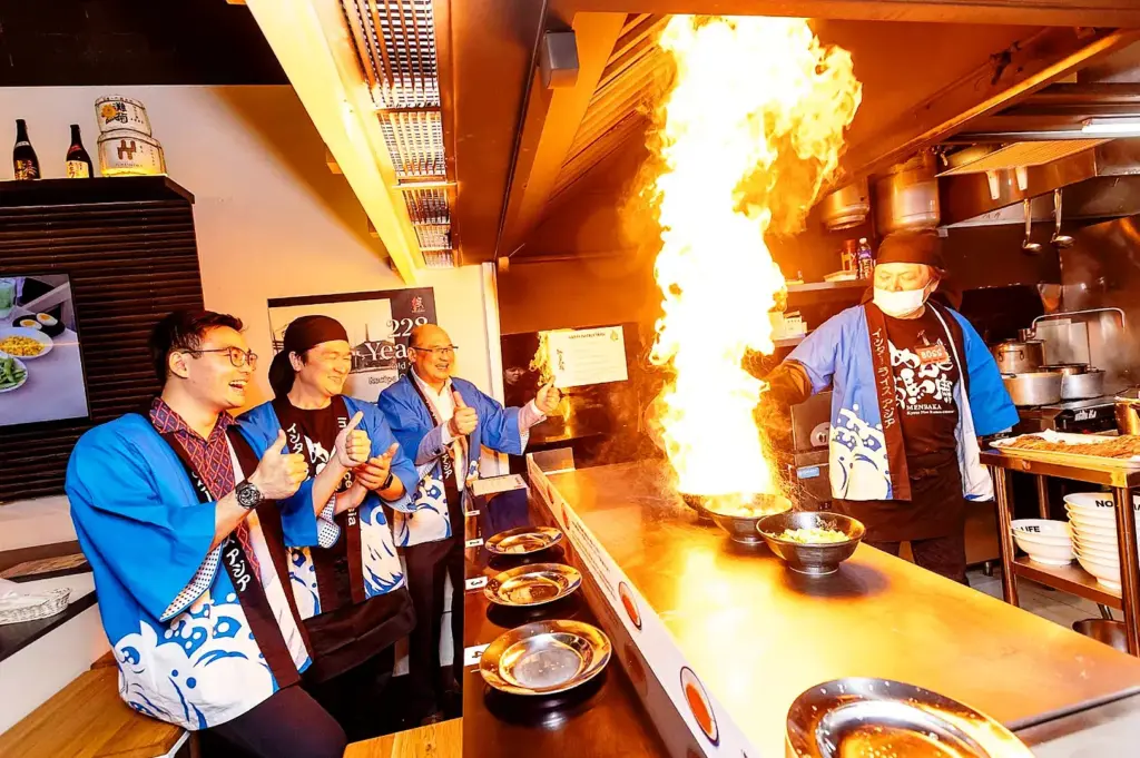 Fire ramen cooking performance at Japanese izakaya with chef igniting flames over ramen bowl, immersive dining experience in Singapore