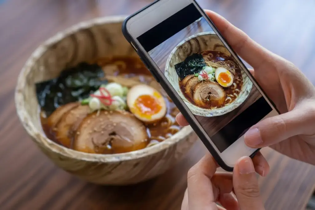 hand holding an iPhone capturing the Ramen bowl