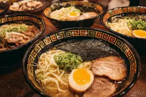 Four bowls of ramen noodles with pork slices, boiled eggs, seaweed, and green onions.
