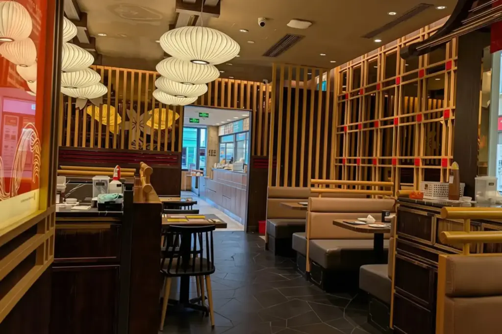 Empty Le Shrimp Ramen dining area with pendant lights, wooden dividers, booths, tables, and counter seating.