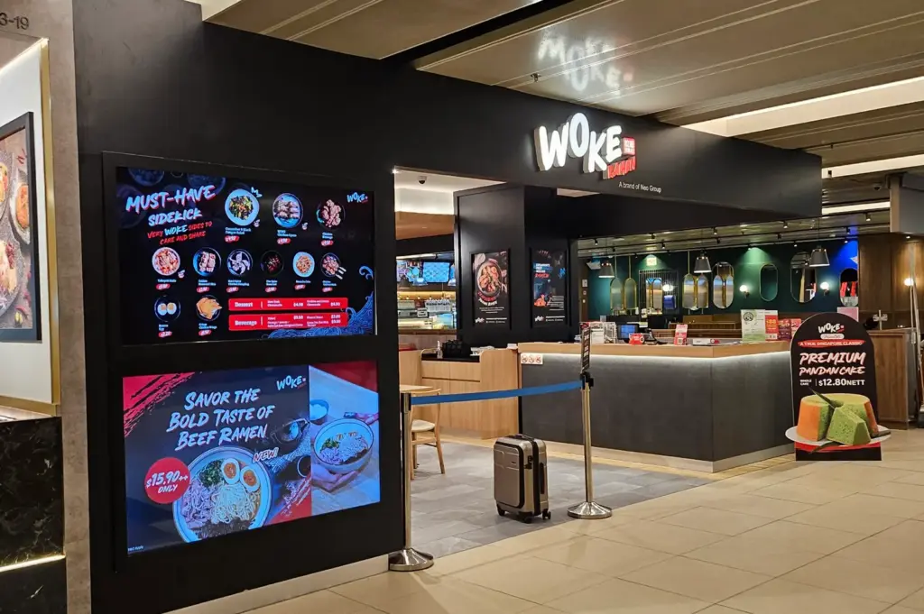 WOKE ramen restaurant interior with menu displays, counter seating, and queue barriers.