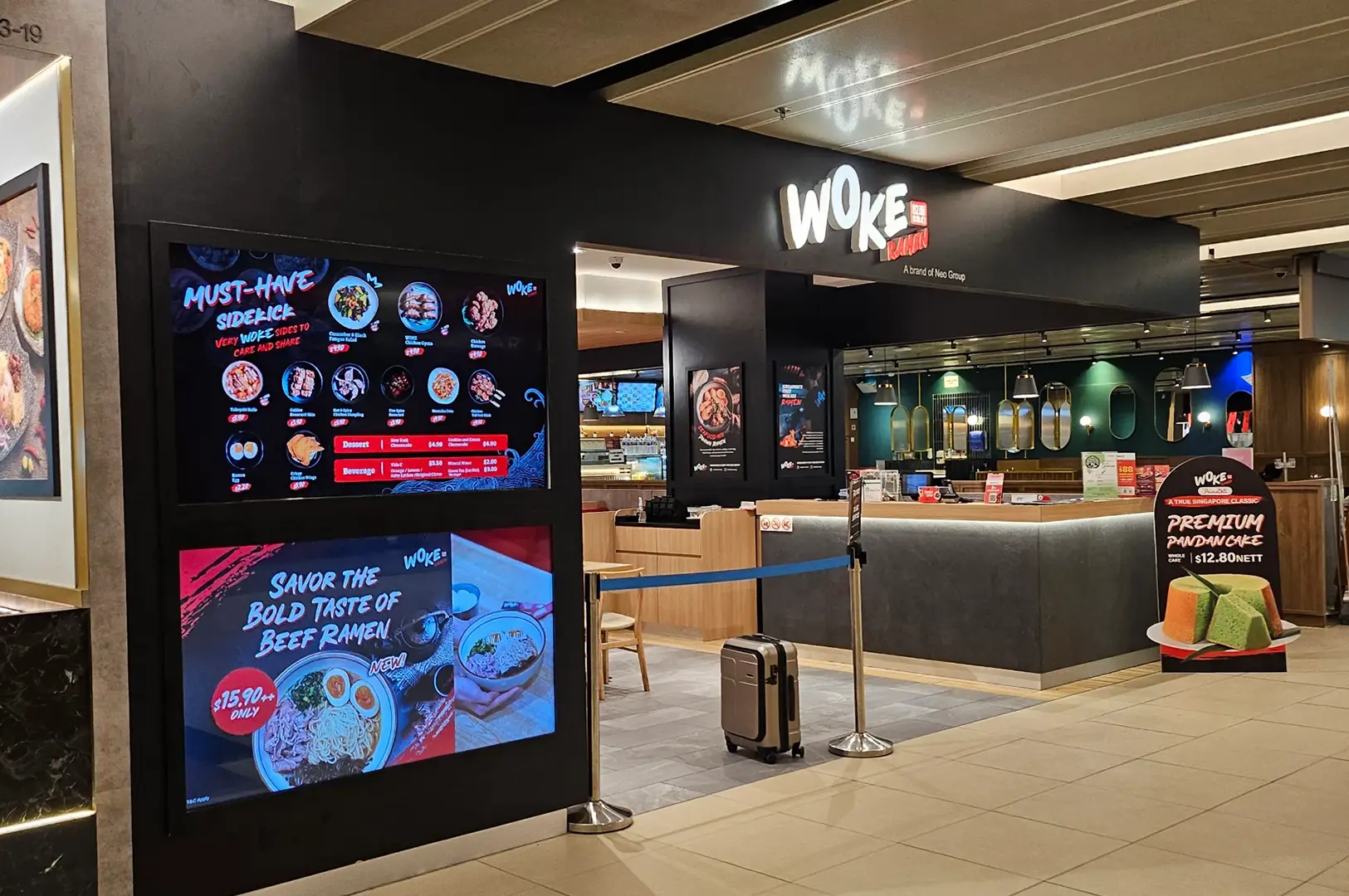 WOKE ramen restaurant interior with menu displays, counter seating, and queue barriers.