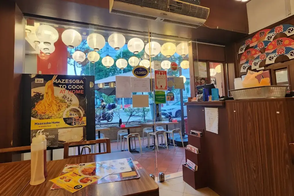 Ramen Matsuri interior with wooden tables, Japanese lanterns, a counter, and a window overlooking the street.