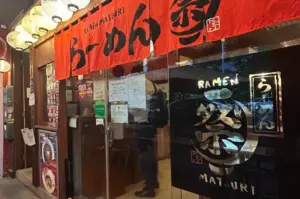 Ramen Matsuri entrance with red Japanese noren curtains, illuminated signage, and glass doors.